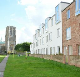 A row of townhouses with a playground and a church in the background at Parrotfish Bay Southwold