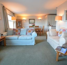 A living room with two sofas a dining table and chairs and side tables with lamps at Crabbe House in Aldeburgh