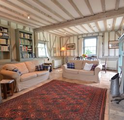 A living room with two beige sofas a red patterned rug built in bookshelves and a dining area at The Gig House Stowupland