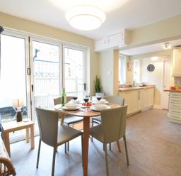 A kitchen and dining area with a round table and four chairs near glass doors at Spindrift Southwold