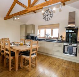 A kitchen with a dining table and wooden chairs at The Mulberry, nr Bungay