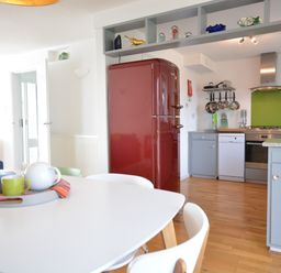 A kitchen with a red refrigerator gray cabinets and a white dining table with cups and a teapot at Aldeburgh Lodge Gardens in Aldeburgh