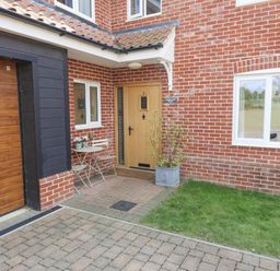 An outdoor entrance with a door, table, chairs, and garage at Meadowsweet, Blythburgh