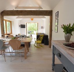 A dining area with a table set for four and a living room with a yellow rocking chair at Red Poll Barn Spexhall Near Halesworth
