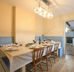 A dining room with a table set for six with wine glasses and bowls and wooden chairs at Walton House Southwold