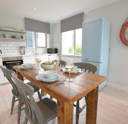 A kitchen with a wooden dining table set for four with bowls and glasses at Sweet Pea Southwold