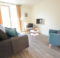 A living room with sofas armchair coffee tables and a wall-mounted tv at Mycroft Southwold in Southwold