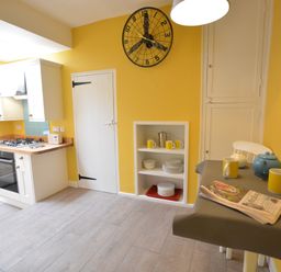 A kitchen with a stove oven combination a table with mugs and a teapot and a wall clock at Alinka Aldeburgh in Aldeburgh