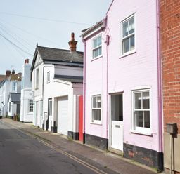 A street view with pastel colored houses and parked cars at Alinka Aldeburgh in Aldeburgh