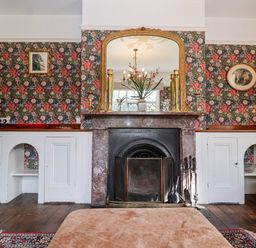 A living room with a fireplace mirror and floral wallpaper at Church Farm Dunwich Near Westleton