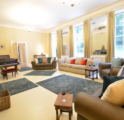 A living room with sofas small tables a piano rugs and large windows at Henstead Hall in Henstead near Beccles