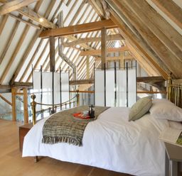 A bedroom with a brass bed and wooden beams at Manor House Barn Peasenhall