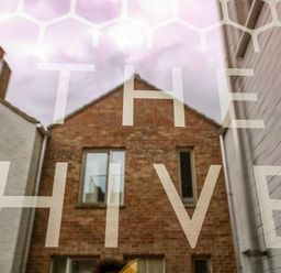A brick house with windows between two white buildings with the text THE HIVE overlaid in Southwold