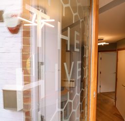 A hallway with a wooden floor and white doors seen through a glass door with honeycomb patterns and the word the hive at The Hive Southwold