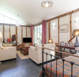 A living room with sofas a wooden coffee table a television and an iron bed at Yew Tree Farm Stable Worlingworth