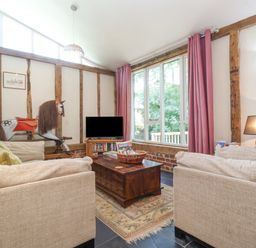 A living room with beige sofas a wooden coffee table pink curtains and a rocking horse at Yew Tree Farm Stable Worlingworth