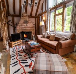 A living room with a sofa, television, and fireplace at Wassicks Cottage, Haughley