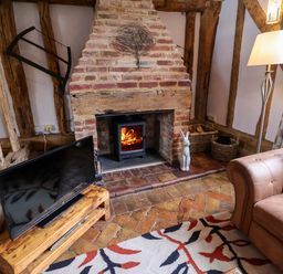 A living room with a fireplace and television at Wassicks Cottage, Haughley