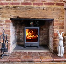 A fireplace with a wood stove and decorative items at Wassicks Cottage, Haughley