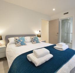 A bedroom with a double bed bedside tables lamps and an ensuite bathroom at Skylight Aldeburgh in Aldeburgh