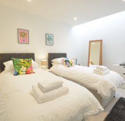 A bedroom with two single beds with white bedding and colorful pillows at Skylight Aldeburgh in Aldeburgh