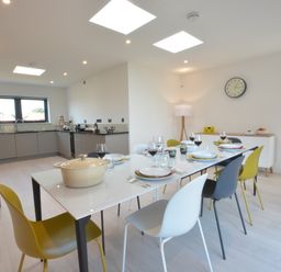 A dining area with a table set for six and an adjoining kitchen in a modern room at Skylight Aldeburgh in Aldeburgh
