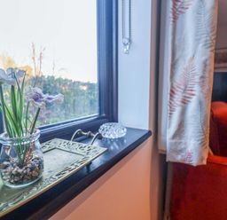 A living room with a window and decorative flowers at Pine Cottage in Woodbridge
