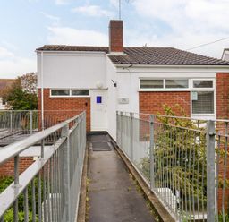 A walkway with railings leading to an entrance door on a two-story brick and white house at The Bridge House Southwold
