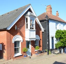 A street view of two adjacent houses one with red bricks and one with light blue walls at The Red Brick House in Aldeburgh