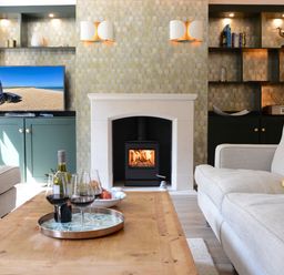 A living room with a fireplace televisions and wine glasses on a wooden table at The Red Brick House Aldeburgh