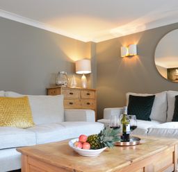 A living room with two beige sofas a wooden coffee table with fruit and wine at The Red Brick House Aldeburgh