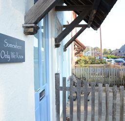 A blue door with a sign that reads Somewhere Only We Know next to a wooden fence at Somewhere Only We Know in Aldeburgh