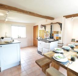 A kitchen with a wooden dining table set with bowls of salad and glasses at The White House with Studio in Wortwell