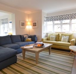 A living room with blue and yellow sofas a wooden coffee table and a striped rug at Mellows Thorpeness in Thorpeness