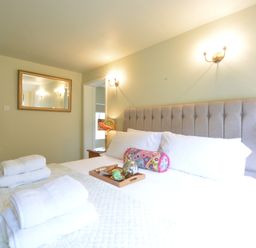 A bedroom with a large bed and towels on it and a mirror on the wall at Church Farm Cottage Dunwich Near Westleton