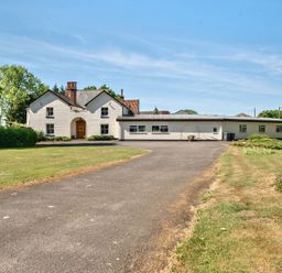 A white house with a wooden door and multiple windows surrounded by grass and trees at Bedingfield House nr Debenham Debenham