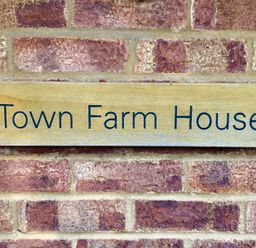 A wooden sign with Town Farm House on a brick wall at Town Farm House Orford