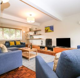 A living room with blue sofas cushions a wooden coffee table a flat screen tv and wall shelves at Town Farm House Orford