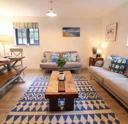 A living room with a sofa and dining table at Corner Cottage, Thorpeness