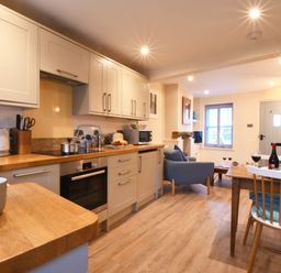 A kitchen and dining area with wooden countertops and a table with wine glasses at Smugglers Rest Aldeburgh