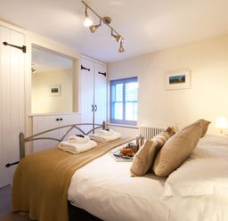 A bedroom with a bed made with towels and breakfast tray by the window at Smugglers Rest Aldeburgh