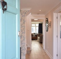 A hallway with wooden flooring leading to a living room with sofas at Napier House Southwold