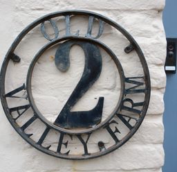 A metal house number 2 sign on a white wall at Old Valley Farm Walberswick