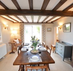 A dining room with a wooden table set for six with plates and glasses at Old Valley Farm in Walberswick