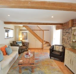 A living room with a sofa and armchairs a wooden coffee table a rug and a cabinet May Barn Ixworth Bury St Edmunds