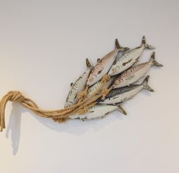 A wall decoration of a cluster of six fish tied together with rope at The Smokehouse Cottage in Southwold