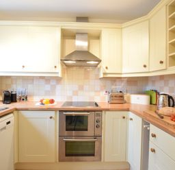 A kitchen with wooden countertops and cream cabinets with various appliances on the counters at Bluebelle Cottage Peasenhall