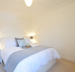 A bedroom with a bed with pillows and a tray with a teapot and cups on it with bedside tables and lamps at Bluebelle Cottage Peasenhall