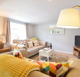 A living room with two sofas a coffee table a lamp and a television at Satis Cottage Westleton