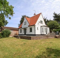 A white house with a red tiled roof and a green lawn at High Ground Reydon in Reydon